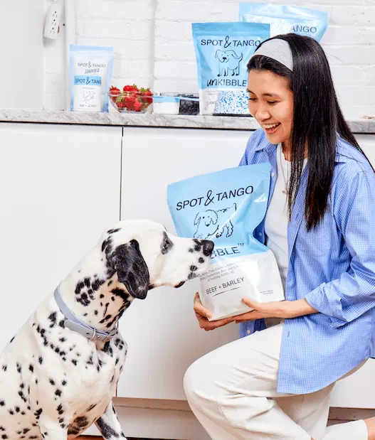 Woman holding bag of unkibble with her dog